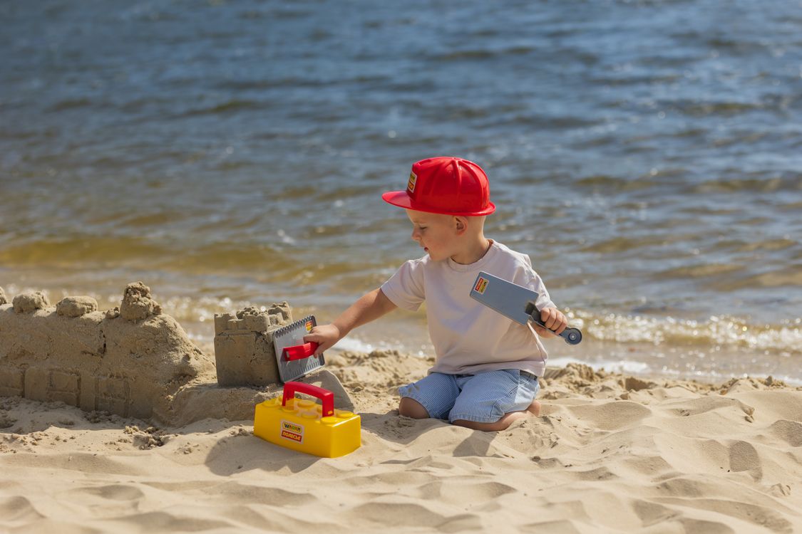 Chłopiec buduje zamek z piasku na plaży, klasyczne wakacyjne wspomnienie do wspólnego wracania